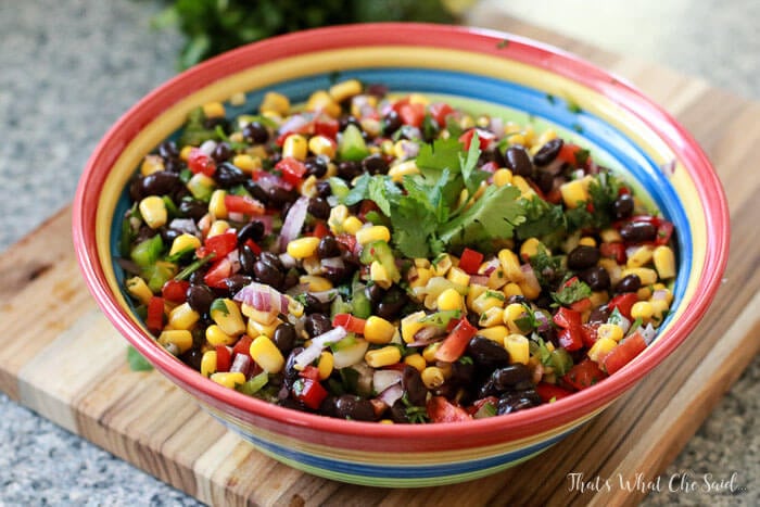 A colorful bowl filled with colorful Corn & Black Bean salsa with cilantro garnish