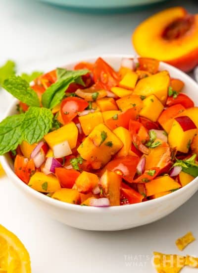 white bowl full of peach salsa with mint garnish