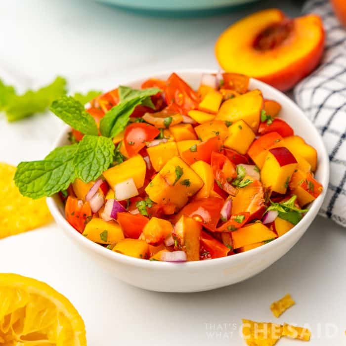 white bowl full of peach salsa with mint garnish