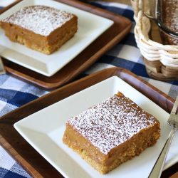 Two Slices of Pumkin Gooey Butter Cake plated with the full cake sheet in the background