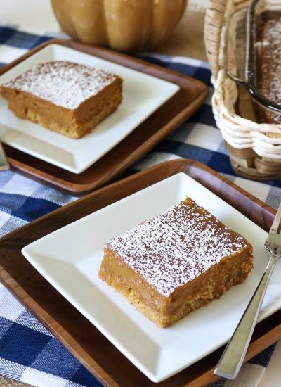 Two Slices of Pumkin Gooey Butter Cake plated with the full cake sheet in the background