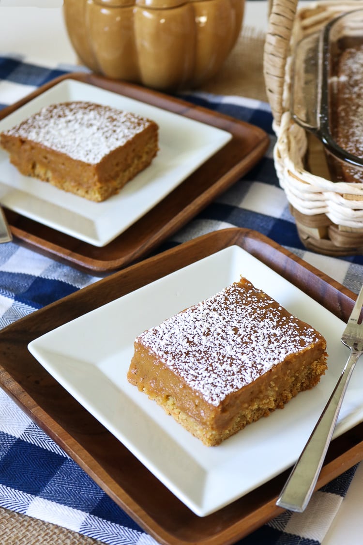 Two Slices of Pumkin Gooey Butter Cake plated with the full cake sheet in the background