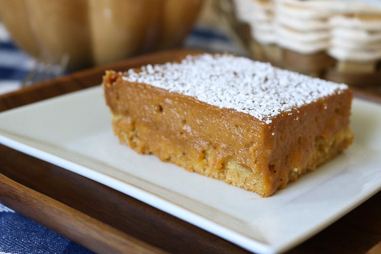 A square slice of Pumpkin Gooey Butter Cake with powered sugar.