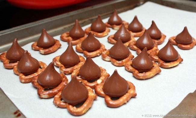 Parchment Lined baking sheet with pretzels and Hershey kisses on the pretzels