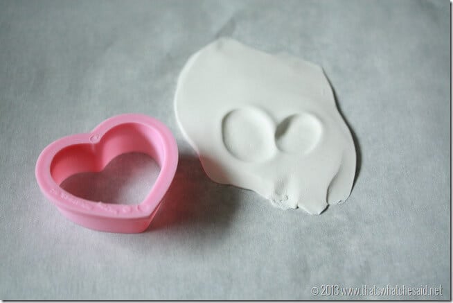 Small heart cookie cutter next to pressed clay with thumbprint v