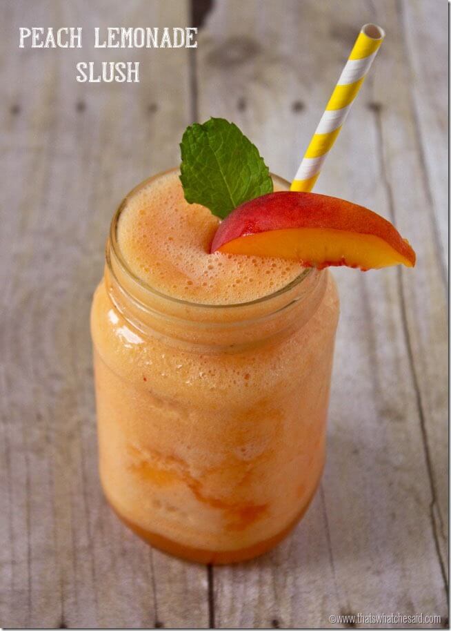 Close up of peach lemonade slushie in a mason jar with a mint leaf and peach slice and straw garnish