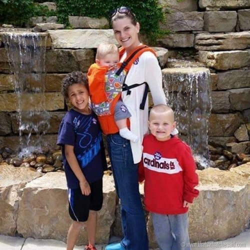 Mom with three boys in front of fountain's waterfall
