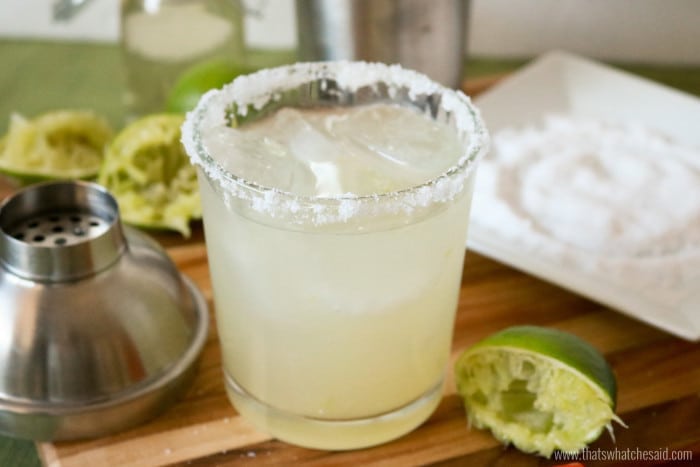 Classic Margarita in a rocks glass with salt rim.  Shaker and salt ingredients in the background. 
