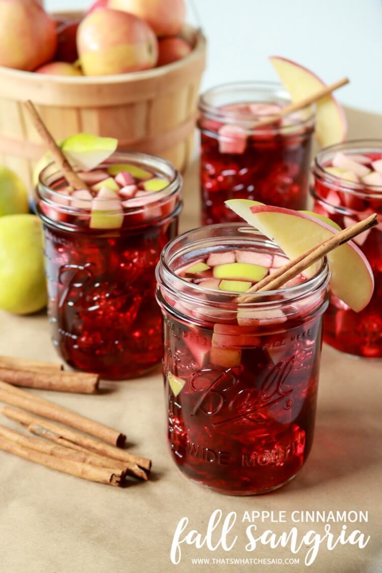 Mason jars of apple cinnamon sangria with apple slices and cinnamon sticks as garnish