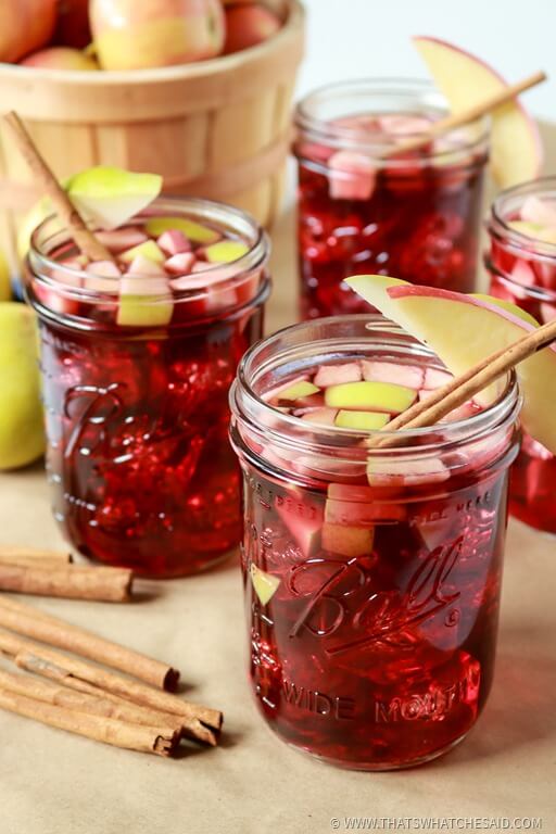 Mason Jars with Apple Cinnamon Sangria, garnished with cinnamon stick and apple slices