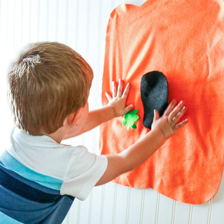 Child adding felt face pieces to a big felt pumpkin shape