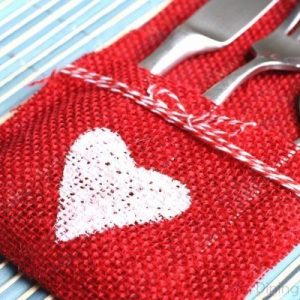 Red burlap utensil holder with painted white heart and twine