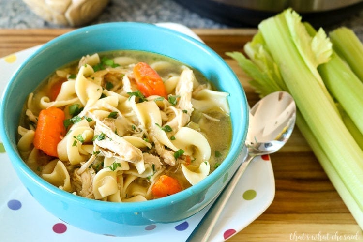 Easy Instant Pot Chicken Noodle Soup - Teal bowl of soup with colorful polka dot plate underneath. Spoon and celery in background