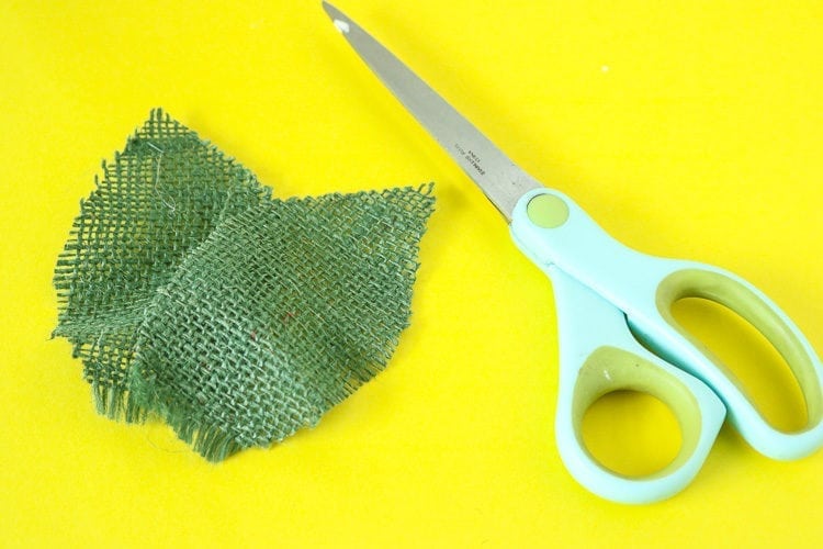 Scissors and green burlap cut into a leaf shape.