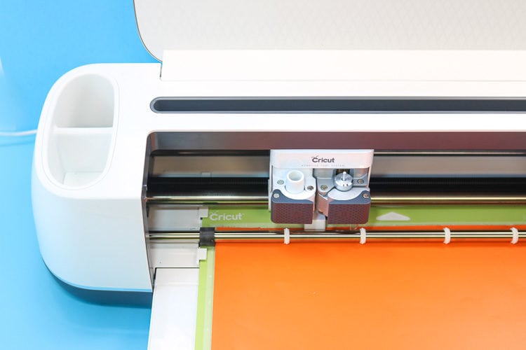 Cricut Maker Machine Loaded with Orange Vinyl on a Standard Green Mat