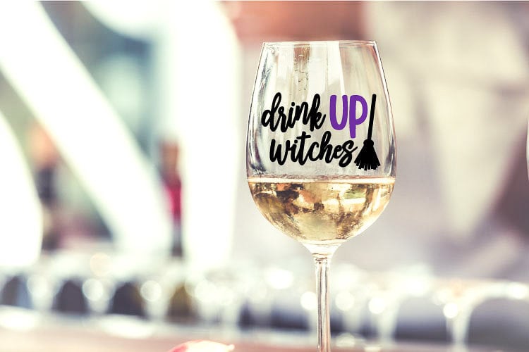 Wine GLass with Vinyl decal that reads "Drink Up Witches" and a broomstick