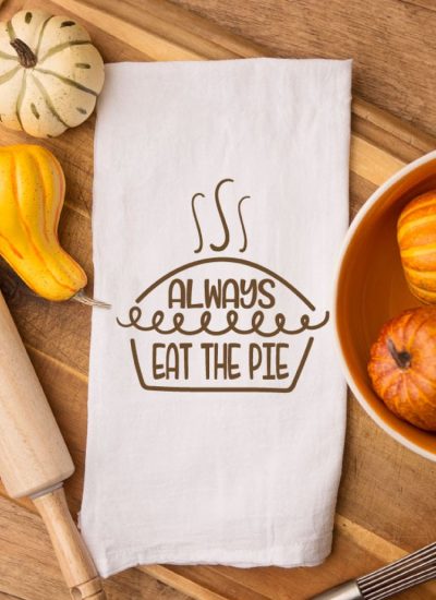 photo of tea towel with the free file iron on on a cutting board with fall gourds around it.