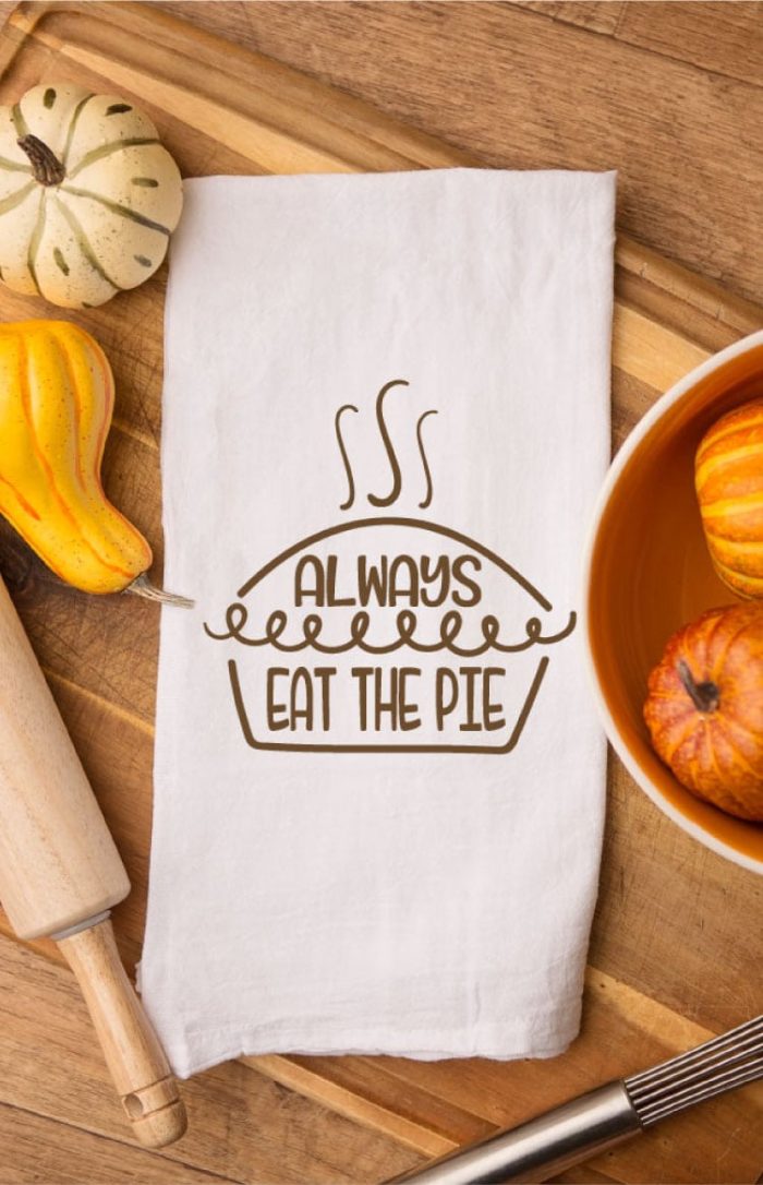 photo of tea towel with the free file iron on on a cutting board with fall gourds around it.