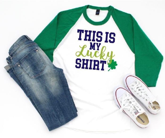 white t-shirt with green sleeves and jeans and white converse.  The shirt has the "This is my lucky shirt" design on it. 