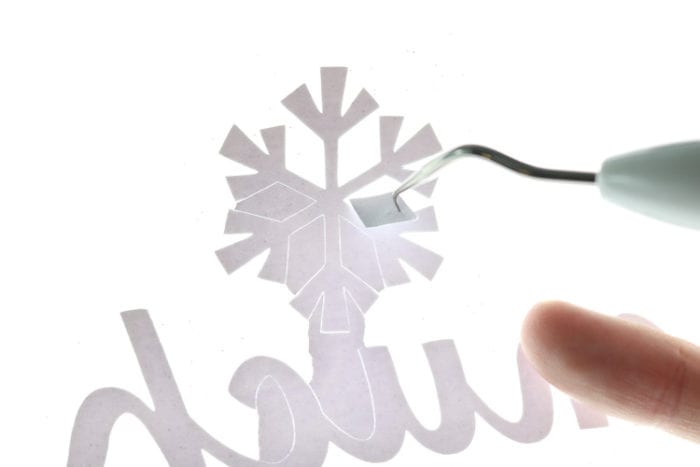 Weeding insides of snowflakes from glitter iron on with BrightPad
