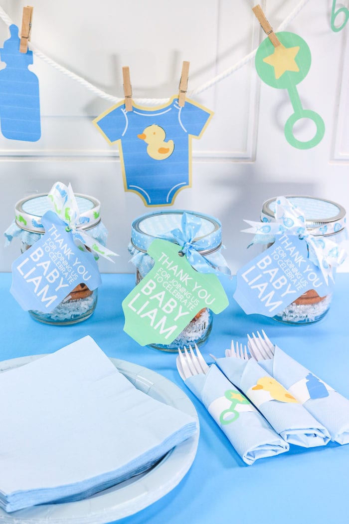 Print then cut Banner, shower favors and napkin rings for baby shower on a white background with blue surface