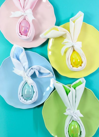 Four pastel plates with matching bunny folded napkins in coordinating colors