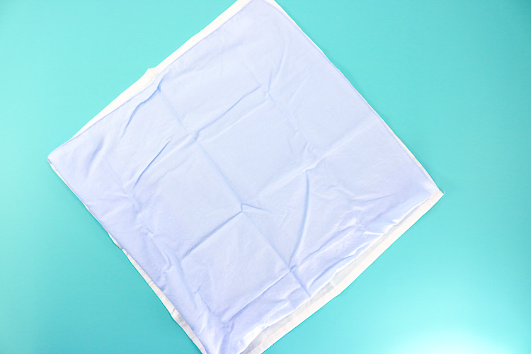 White cloth napkin layered with blue napkin ready for bunny fold