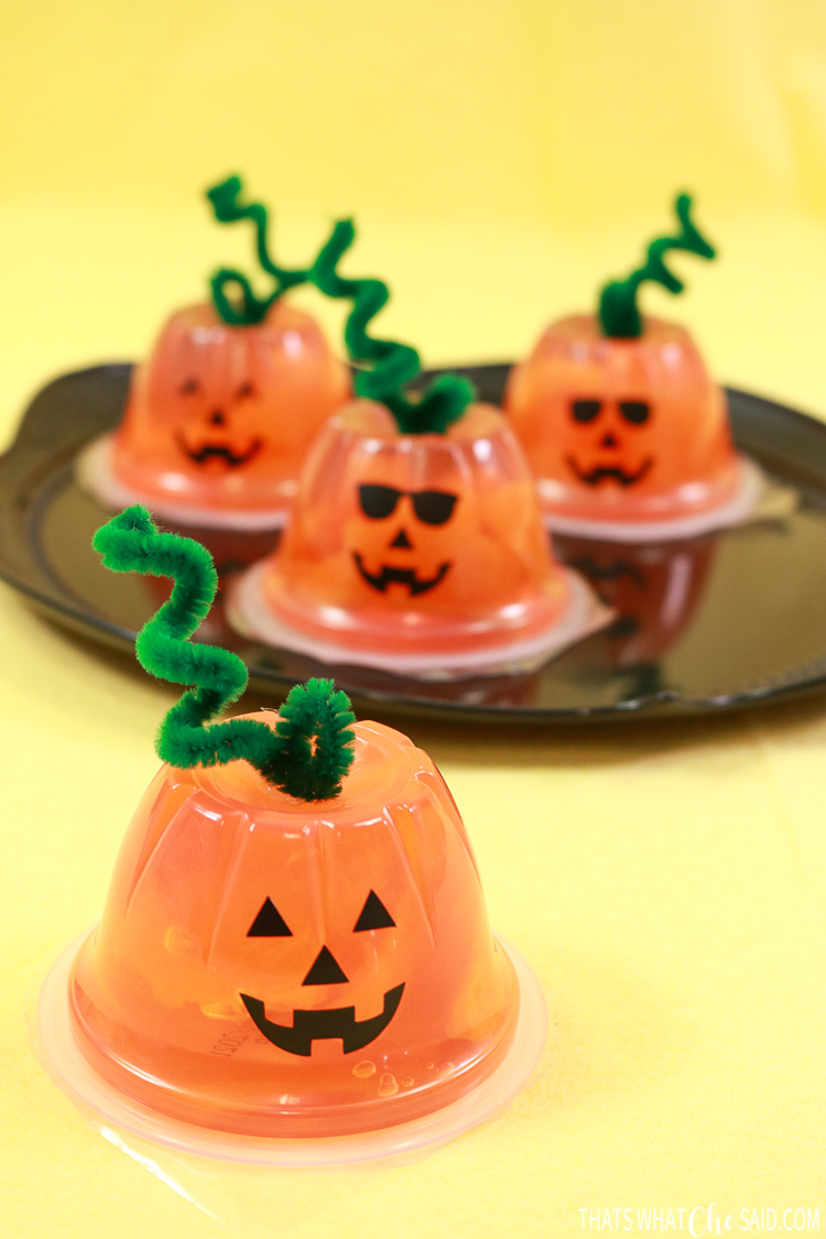 Orange fruit cups turned into jack-o-lanterns with faces and pipe cleaner stems