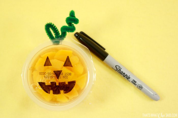 Orange fruit cups turned into jack-o-lanterns with faces and pipe cleaner stems