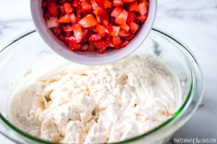 Bowl of whipped cream, and diced strawberries ready to be added