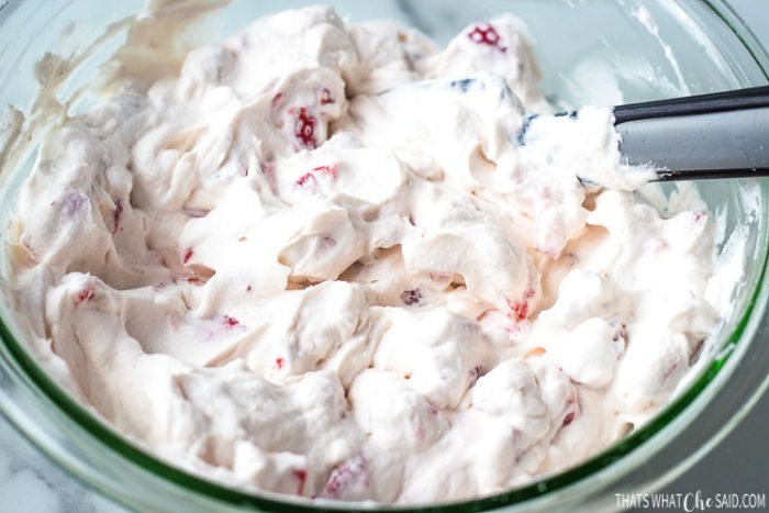 Bowl of fresh whipped cream with fresh diced strawberries folding in