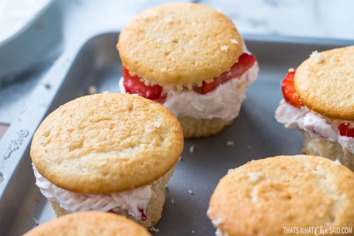 Assembled strawberry cream cupcakes.  Cupcake bottoms, fresh strawberry cream, strawberry slices, cupcake top