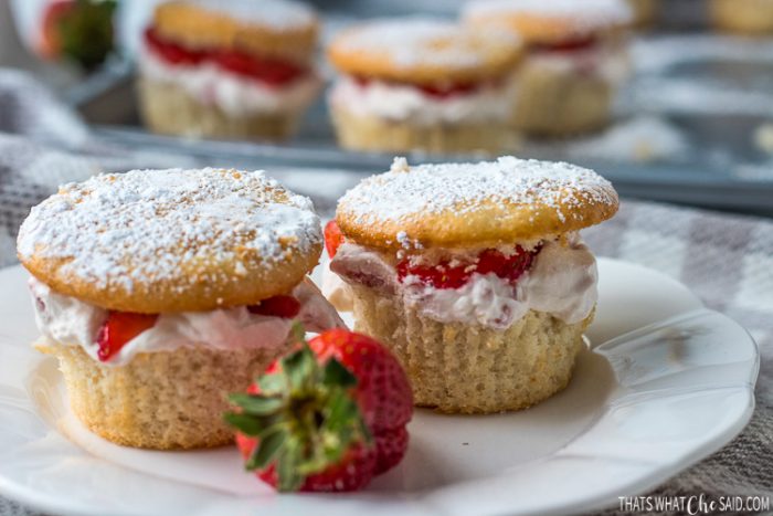 Two Strawberry cream cupcakes on a white plate with a strawberry garnish