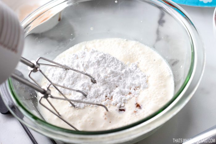 Mixing Bowl with heavy cream, vanilla extract and powdered sugar ready to be whipped