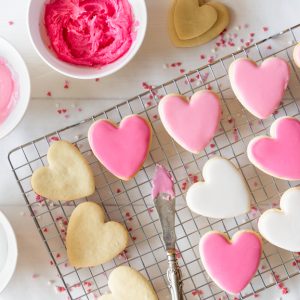 Heart cookies on a cooling rack with different shades of pink and white royal icing