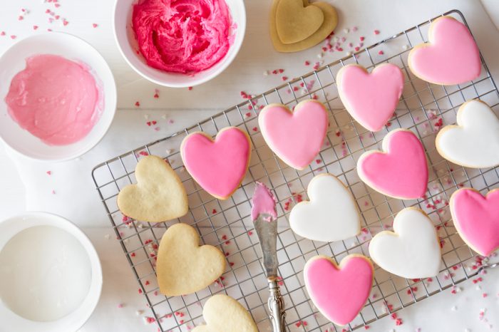 Heart cookies on a cooling rack with different shades of pink and white royal icing