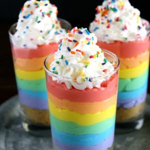 Cheesecake Parfait glasses with cheesecake layers in colors of the rainbow, Whipped topping with rainbow sprinkles on top