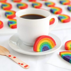 Sugar cookie dough in rainbow colors and shapes with a mug of coffee