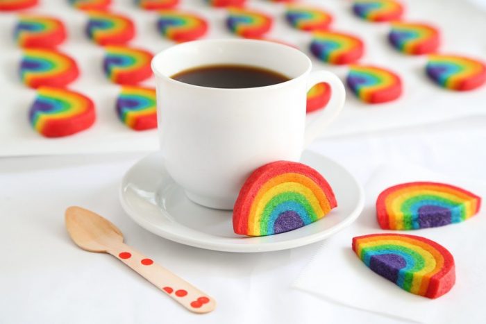 Sugar cookie dough in rainbow colors and shapes with a mug of coffee