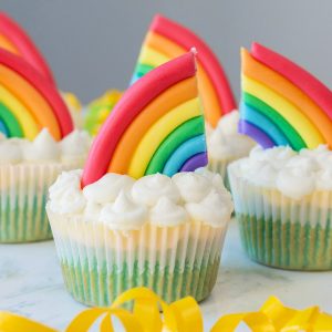 Cupcakes in land, sky and clouds with rainbow accents on top.
