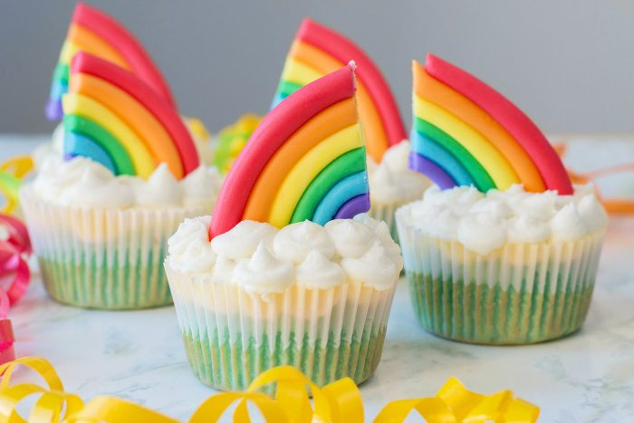 Cupcakes in land, sky and clouds with rainbow accents on top.