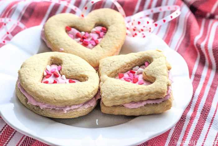 A plate with shortbread sandwich cookies with heart cut outs and valentine sprinkles