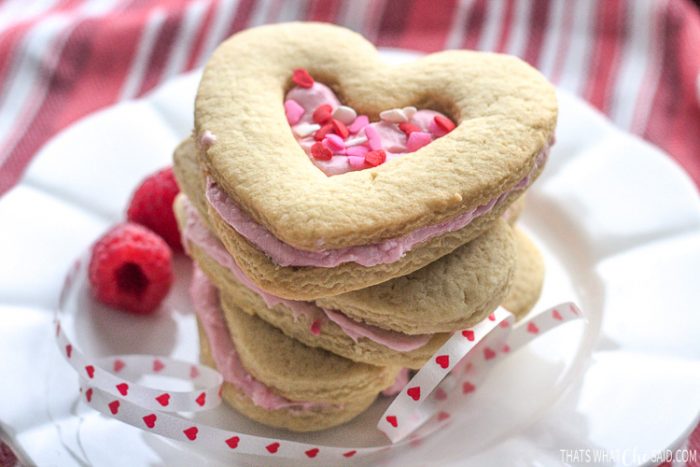 Shortbread heart cookies sandwiched with raspberry filling stacked on a plate