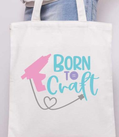 Vertical - Someone holding a canvas tote with the "born to craft" svg design with glue gun applied in iron vinyl