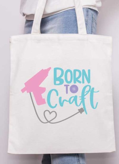 Vertical - Someone holding a canvas tote with the "born to craft" svg design with glue gun applied in iron vinyl