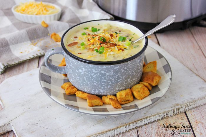 Cheeseburger Soup in a camp mug on a buffalo check plate with croutons