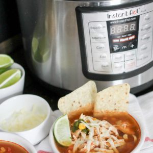 Chicken Tortilla soup with instant pot, limes and cheese in background