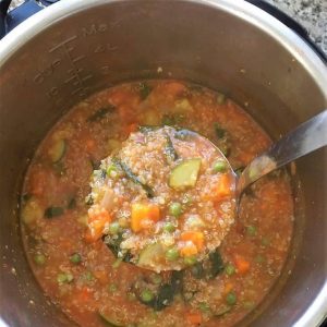 Shot looking down into the instant pot of soup with ladle full of Vegetable Quinoa Soup