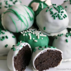 Close up of green and white chocolate covered oreo truffles. One truffle is cut in half to show insides