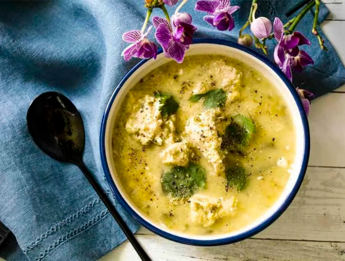 Bowl of Chicken Poblano soup on top a blue napkin with spoon